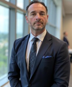Headshot of Joshua Corbelli in a suit inside of an office.